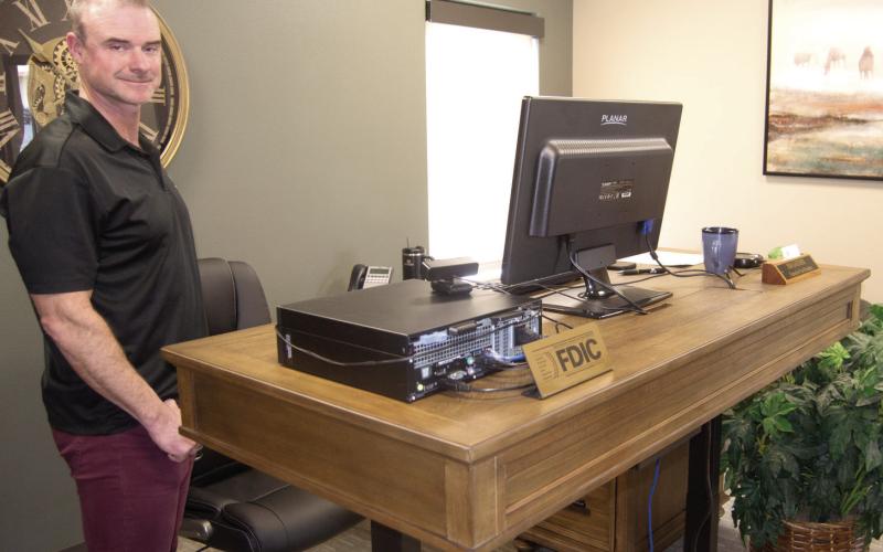 Vice President Jim Gaither demonstrates his new multiple level desk allowing the user to work seated or standing.