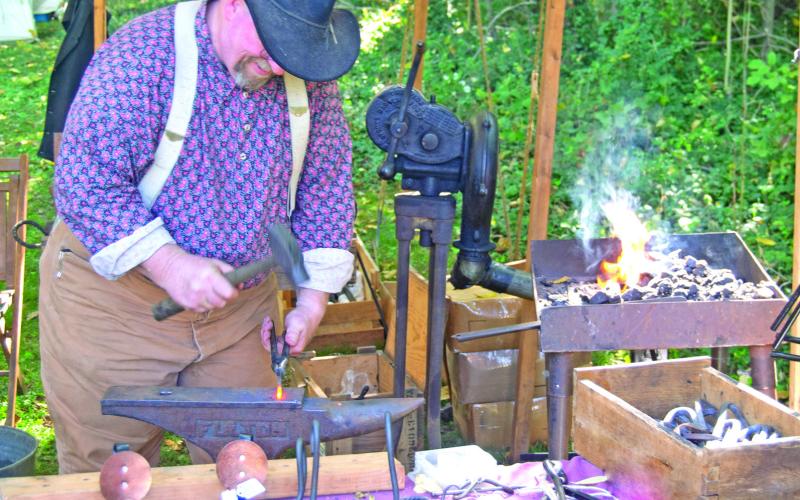 Pounding out metal utensils used in the camp, Jim Friend is kept as busy as a real army blacksmith.