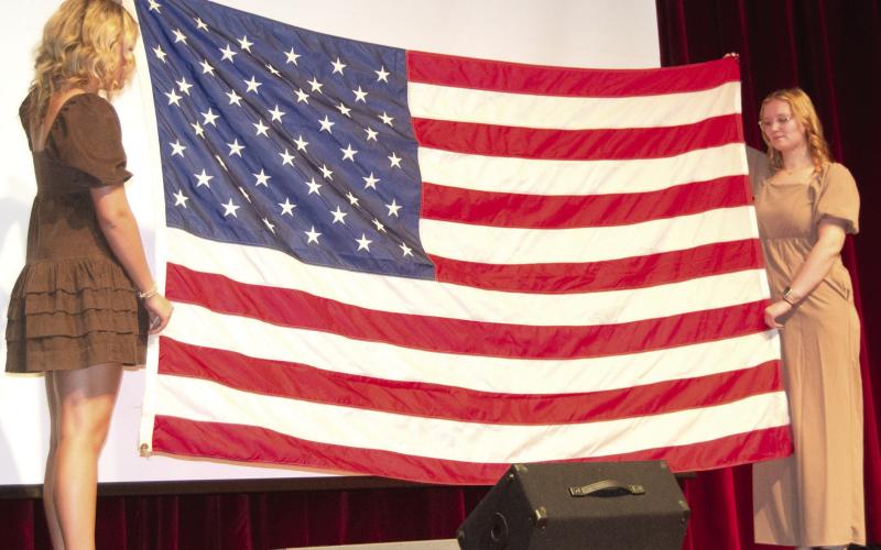 Flag bearers Kenadie Carter and Chloe Rogers ended the Veterans Day program by folding the flag as Mallory Thompson and Lydon Lovesee played “Taps.”