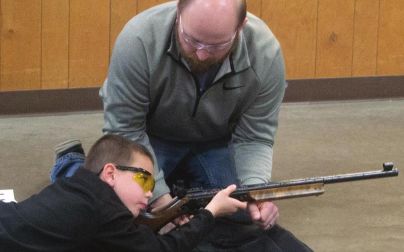 Columbus 4H Club BB Gun Competition Coordinator Dustin Major helps contestant Trevor Lacen to aim his rifle during the Monday, January 17 event. Fifteen local youths competed throughout the afternoon. Photo by Jacob Spencer.