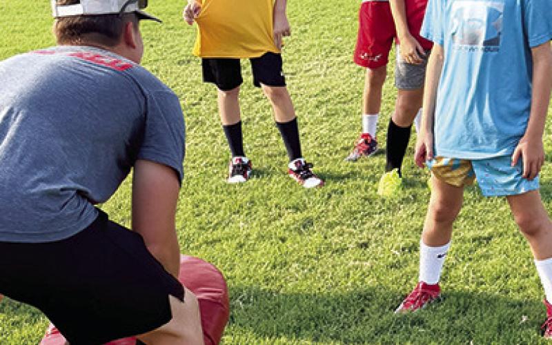 Brody Carter, Titan Junior, helps Kolt Crain, Drake Hamilton, Abel Ellison and Lee Snow with their drills during workouts, Thursday at Titan Stadium. The camp was held for tackle and flag football players in USD 493 grades three through six.