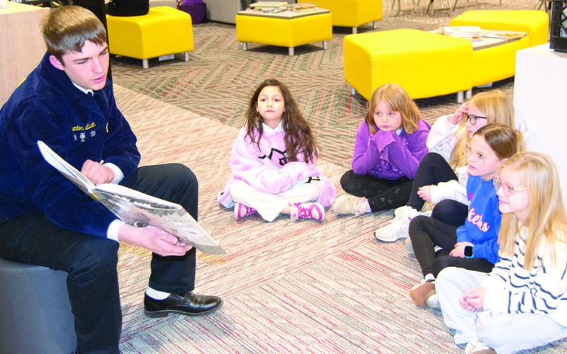 Columbus High School FFA member, Trenton Lacen reads to Amyx Evans, Taylynn Midgett, Brynn Bownan, Harley Sherrill and Adeline Salas, Caitlin Creech’s third graders at Central Elementary. Reading took place at the Central Elementary library as part of national FFA week. News Report photo by Tanya Woolsey.