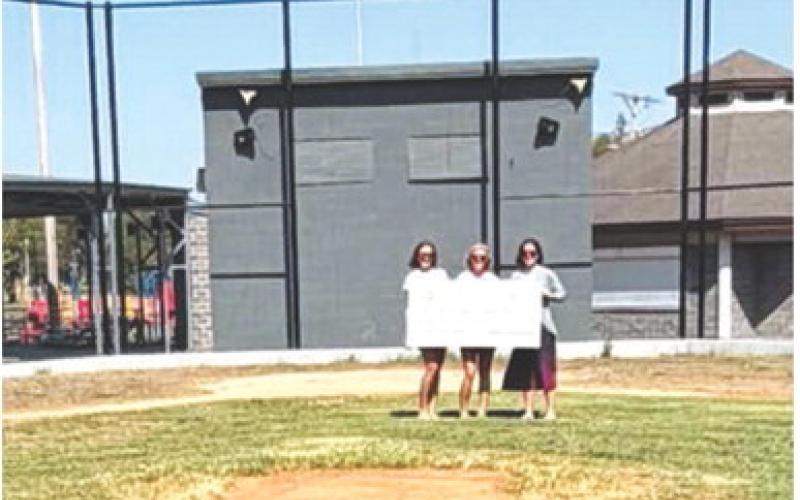 Members of the Columbus Recreation Commission accepted a grant from the Columbus Area Community Foundation for improvements to the Cal Ripken (Volunteer) Field and the girls softball field recently at the Columbus Community Field Ball Park. Keli Benedict, Miranda Eaton, and Kelly Walters are shown with the check and the backstop improvements made on the Cal Ripken (Volunteer) Field over the summer. Courtesy photo.