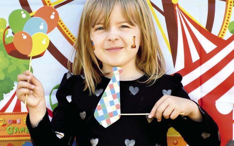 Park elementary kindergarteners celebrated the end of the school year with some last minute carnival fun. Teachers set up and launched a mini carnival at the school including multiple activities. They had a tattoo station, catch the ducks station, boardwalk game, outdoor tic tac toe, ribbon wand fun and popcorn and cotton candy. Meredith Moore shows her tie and balloons in front of the carnival poster. Photo by Tanya Woolsey.