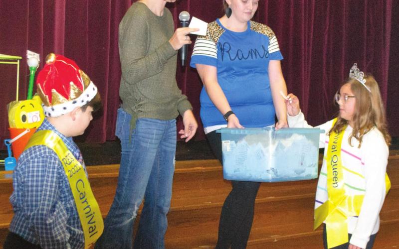 First Grade Teacher Carli Miller stands on stage in Riverton High School’s auditorium with the PTO Carnival King Colton Bebee and Queen Paige Boyes. The students are seen helping her draw tickets for prize money awarded to three of the event’s lucky attendees. Photo by Jacob Spencer.