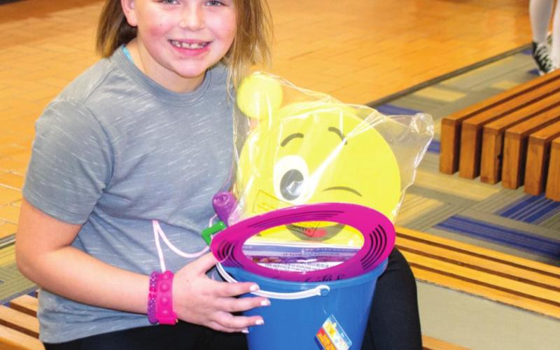 Student Wylie Burrows (above) poses for a picture after earning a runner-up position for the PTO Carnival Coronation. The young lady holds a bucket of toys she won for her high ticket sales prior to the event. At right, Shawna Andrews, Ana Carver and Maddox Carver all pose for a picture at Riverton School District’s PTO Carnival on Saturday. The girls and many of their peers all had fun making their way around the school playing various skill-based games. Photos by Jacob Spencer