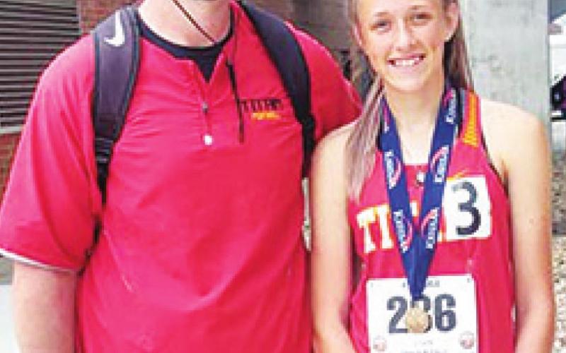 Lady Titan Sophomore, Montana Ohmart is congratulated by coach Blake Burns on her third place medal in the 1600 Meter Run at the 2021 Kansas Class 3A State High School Track and Field Meet at WSU’s Cessna Stadium, Friday. Montana re-established her school record with a time of 5:27.88 minutes. Courtesy photo.