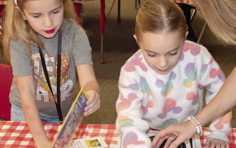 Hallie Bole and Reece Tedlock choose their books for the kindergarten book tasting. In celebration of Read Across America Week, students recently moved to different classrooms with a different book experience in each room. First graders assisted, passing around new books as they finished and helping them read the books they selected. News Report photo by Tanya Woolsey.