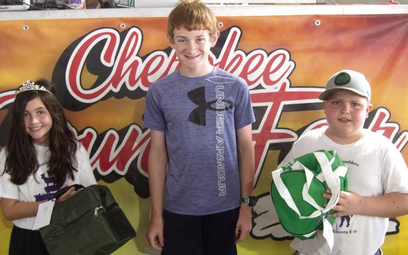 Lydan Atkinson (center) won the Grand Champion four-seven years in project color photo and Overall Champion photo. Queen Addison Coke and King Titus Woods presented the awards