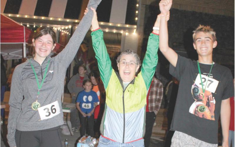 Band director Gae Phillips congratulates two of the winners of the Zombie run sponsored by the Columbus High School Band. The Zombie Run is looked forward to by many runners in the area.