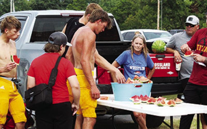 The tradition continued as the The Titan Booster Club provided watermelon for players following the annual Lawn Chair Scrimmage. Cord Saporito, Kip Noel, Jonas Stover, Dane Merrick and new assistant coach Brett Hamilton enjoy the treat provided by boosters Karrah Smith and Clint Saporito.