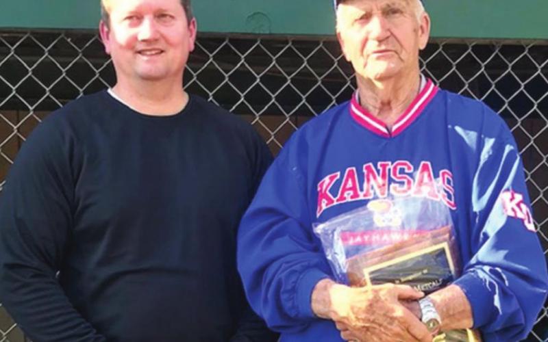 Wayne Metcalf was presented a plaque by Baxter Springs Little League President, Bill Buck, during opening ceremonies recognizing the long time volunteer for his 55 years of service to the league and community. A new scoreboard was erected to officially renamed the local field as Wayne Metcalf Field. Photo by Dee Riley.