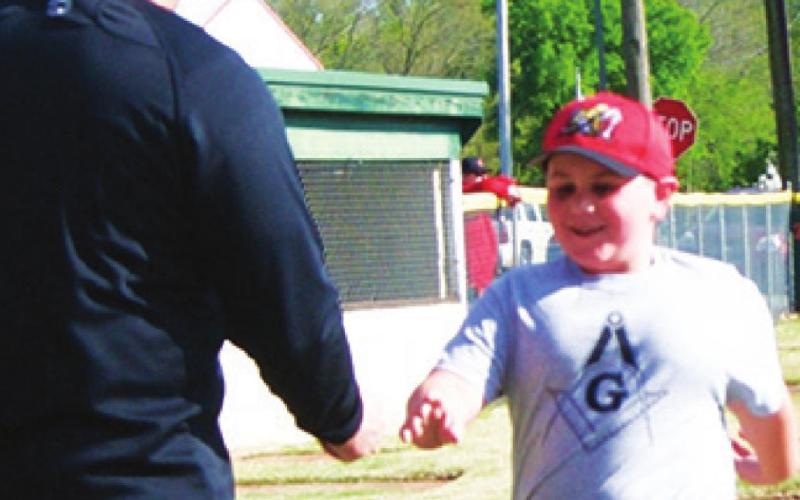 Tatum Shultz received a $100 Academy gift card from league president, Bill Buck for being top in the minor league candy sales at the Baxter Springs Little League opening ceremonies. Photo by Dee Riley.