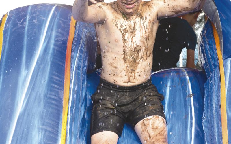 Rainy conditions did not stop youngsters from enjoying the water slide at the annual Freedom Fest sponsored by Columbus Fire Department. Westin Patton was covered in mud as he took his turn down the inflatable set up at Columbus City Park.