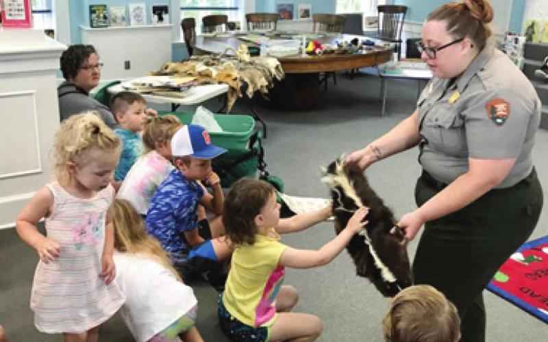 Park Ranger Sarah Martin with George Washington Carver National Monument in Diamond, Mo., brought an array of animal pelts to show the children at the Johnston Public Library Tales and Tails program. One of the pelts was from a skunk. The next program is scheduled for June 24 and a pet show is planned. Photo by Dee Riley.