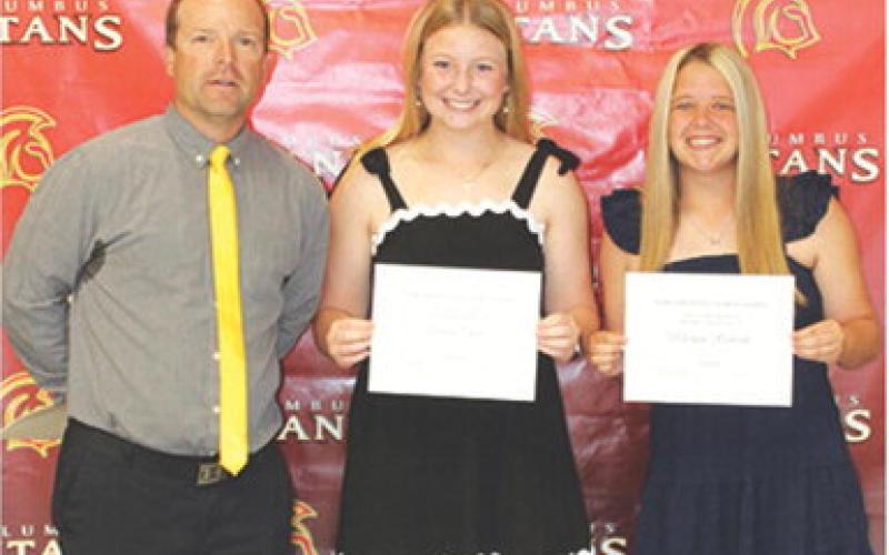 Seniors, Trinity Green and Morgan Richards, received the Tom Goettel Scholarship in the amount of $1,000 each from USD 493 Staff Member, Jerry Smiley, during the 2026 Senior Assembly, May 15, at the Columbus Unified High School Gymnasium.