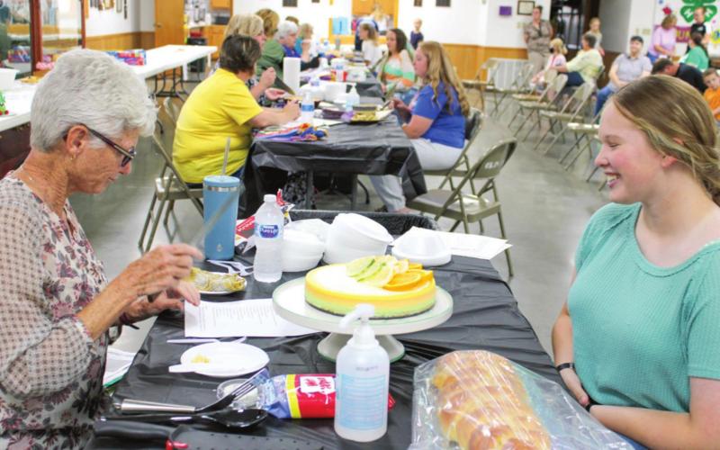 Emma Walker, 4-H member, speaks with one of the judges during the foods show. Walker explained her projects to the judge, discussing ingredients, methods and other facets of her entry.