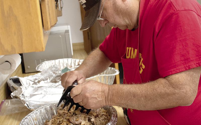 Ron Holmes is hard at work “pulling” the pork for sandwiches on June 17 for a benefit dinner to support Ed Semonick. The benefit went through more than ten roasting pans of pulled pork, most of it was sold within the first hour.
