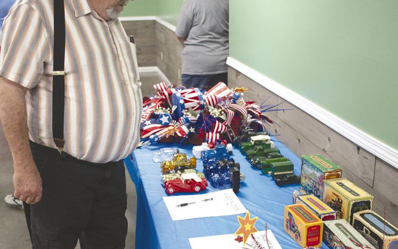 Fromer Judge Sam Marsh peruses silent auction items available for bid at the Ed Semonick benefit dinner on June 17. Among the items were a variety of Avon car bottles (inset).