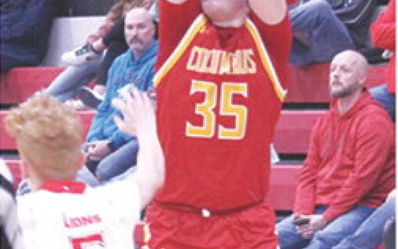 Titan Senior, Jett Tanner, makes one of his four, three-point shots to lead Columbus with 16 points in their 46-50 loss in Baxter Springs, Monday. Sophomore Logan Abbott defends for the Lions.