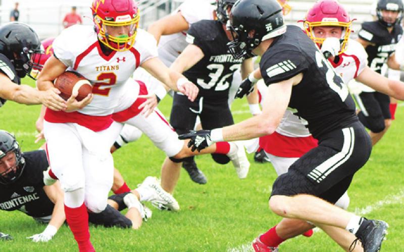 Leaving a wake of Raider defenders behind him, Titan Senior Quarterback, Jaxson Haraughty, makes his way to a first down during the first Columbus possession Saturday, in the rain delayed finish of the Friday season opener in Frontenac. Junior, Landin Midgett, helps clear a path in his final play of the season after suffering a broken tibia on the play. Haraughty exited the game later with an ankle injury and is awaiting word on the possibility of his return to the field.