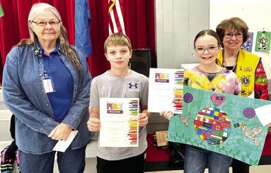 Marla Larison presented Baxter Springs winners of the Peace Poster contest with their awards. Jacob Busse placed third and Andee Chesnut placed first. Second place winner Caylor Bilke is not pictured. Debbie Hopkins was also on hand for the ceremony. Photo by Dee Riley.