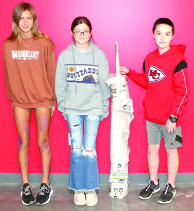 Students in Nicholas Weber’s seventh grade science class used the metric system to build scale models of the North Tower in commemoration of the 911 anniversary. The models were built using newspaper and tape with the requirement that it had to stand alone when completed. Addilyn Wilson, Maddie Duling, Ryker Youngblood show their tower.
