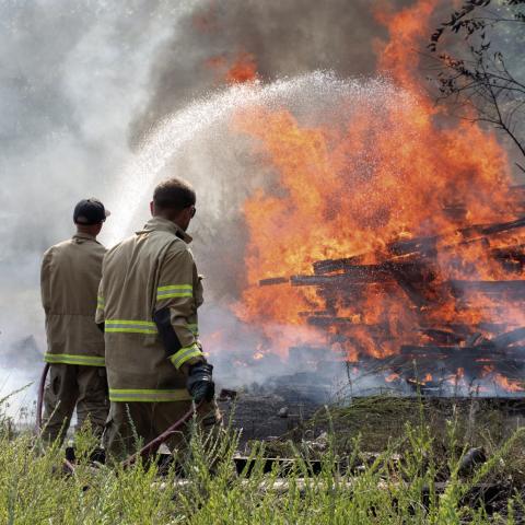 What started as a small fire Monday afternoon quickly spread to engulf multipole acres including a file of more than a hundred railroad ties. Columbus Fire Fighters Kale Kitterman and Cody Burton work to contain the large fire as part of a six-man, three apparatus crew that responded to the fire.