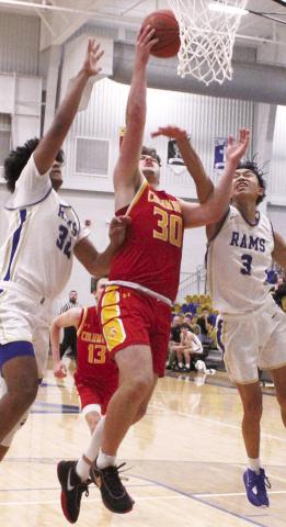 Titan Senior, Brett Hamilton, goes in for two points between Ram Senior, Jamey Richardson and junior, Zach Feldkamp in the final minutes of the, 59-48, Columbus win in Riverton, Friday.