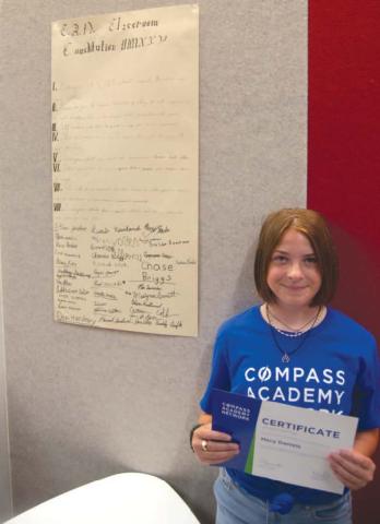 Standing beside the Classroom Constitution developed by the Compass Academy students during their recent session. Misty Daniels is pictured by the Civics work.