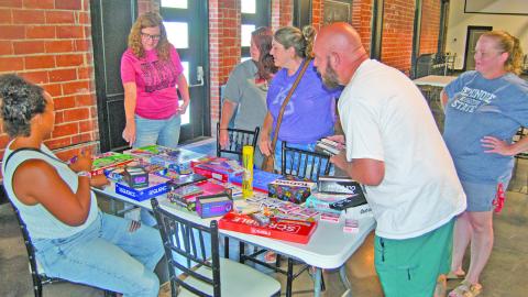 The Columbus Library sponsored Game Night drew families to play several games. The event held at the State Theatre Event Center. Librarian Lauren Dainty hands out games to the players.