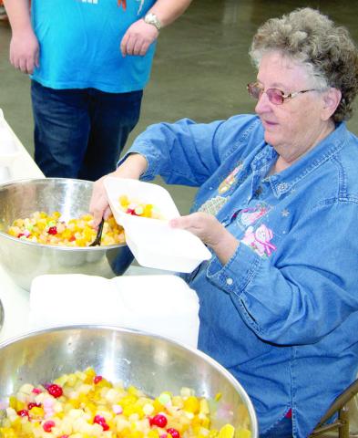 Robin Jones fills fruit cocktail bowls Saturday morning before the crowds arrived. She has been providing a Christmas community dinner for 30 years. Which she says she could not do without a lot of helpers.
