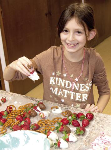 The 4-H Winter Fun Camp Day kept youngsters busy with crafts such as Angelina Capron dipping strawberries in chocolate for a Christmas treat. The day included crafts, cooking, robotics and more.