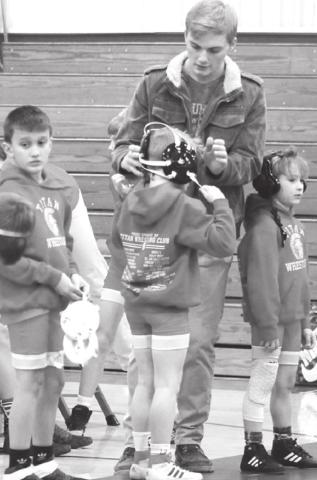 Columbus Wrestling Club Coach, Sylas Stone, assists his wrestler with headgear adjustments prior to the club’s exhibition matches on the varsity mat at the CUHS Gymnasium, Thursday.