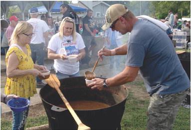 Junior Collingsworth dips chili from the large caldron Friday evening as the Weir Homecoming got underway. The free chili and beans cooked all day over a wooden fire. Several hundred people were served at the event.