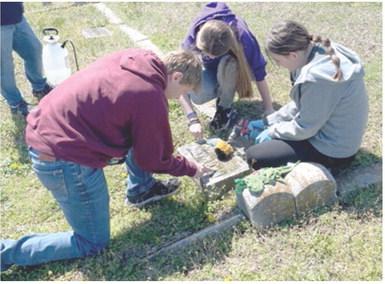 Seventh grade students at Southeast Middle School participated in a day of service April 8. Gavin Potts, Kylee Emerson, and Kinzey Mitchell were cleaning headstones at Cherokee Cemetery. Students also picked up litter on Highway 7. Sons and Daughters of the American Revolution assisted with supplies explained historical preservation techniques. Courtesy photo.