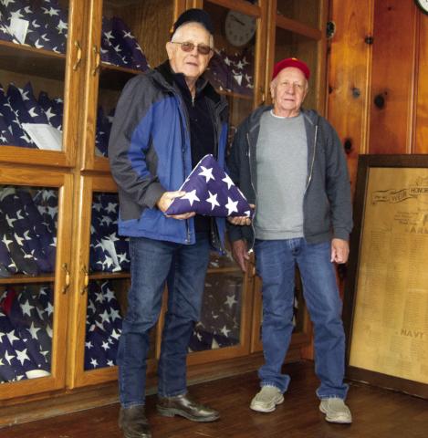 Standing before a cabinet filled with flags belonging to families of veterans from Weir. Larry Spahn, representing the American Legion and Milt Alexander representing the Weir Civic Club are seeking to give veteran’s flags to their family members.