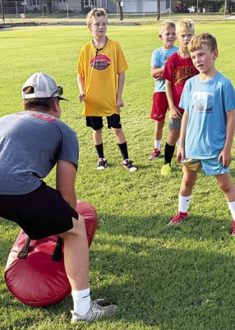 Brody Carter, Titan Junior, helps Kolt Crain, Drake Hamilton, Abel Ellison and Lee Snow with their drills during workouts, Thursday at Titan Stadium. The camp was held for tackle and flag football players in USD 493 grades three through six.