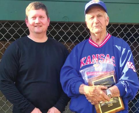 Wayne Metcalf was presented a plaque by Baxter Springs Little League President, Bill Buck, during opening ceremonies recognizing the long time volunteer for his 55 years of service to the league and community. A new scoreboard was erected to officially renamed the local field as Wayne Metcalf Field. Photo by Dee Riley.