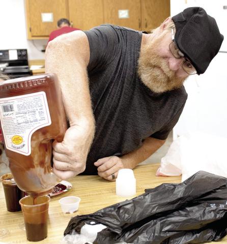 Aron Davolt worked to prepare barbecue sauce containers for to-go meals during the benefit dinner held for longtime Columbus barber Ed Semonick June 17.