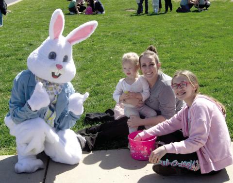 A visit with the Easter Bunny following the Baxter Springs Kiwanis Club Easter Egg hunt at the High School on Saturday. Piper McMillen is held by Amanda Maghe while Josie Stewart checks the egg basket.