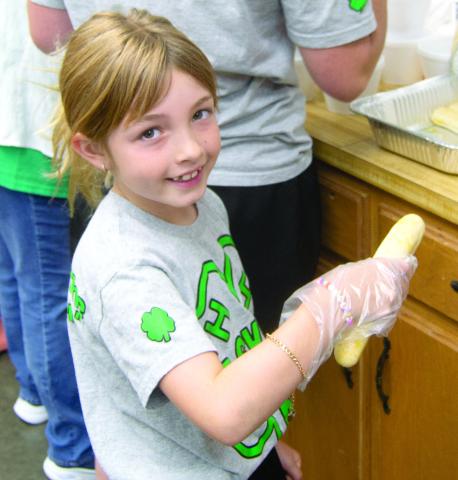 Everybody was helping at the very successful 4-H building fund raiser June 7. The funds will be used to remodel the building. Elle Jesse had the job of putting bread sticks in the spaghetti dinner.