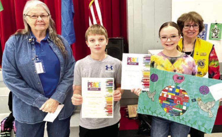 Marla Larison presented Baxter Springs winners of the Peace Poster contest with their awards. Jacob Busse placed third and Andee Chesnut placed first. Second place winner Caylor Bilke is not pictured. Debbie Hopkins was also on hand for the ceremony. Photo by Dee Riley.