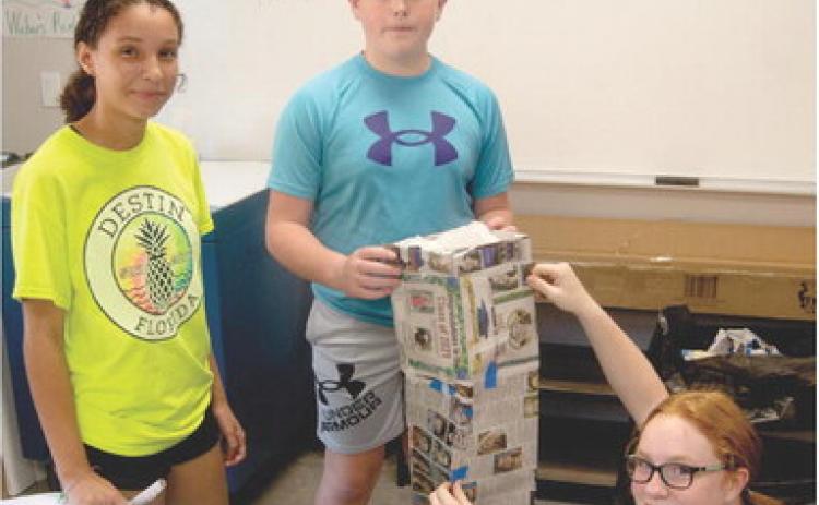 This may appear to be a class building project, but in fact the students in Nick Weber’s seventh grade class at Columbus Junior High School are learning about math, history and construction. They are building out of newspapers, replicas of the World Trade Center tower destroyed September 11, 2011. The students had to convert the building dimensions into centimeters and build a structure that would stand. Working on the project are Salece Marris, Jex Cheney and Mollie Sauerwein.