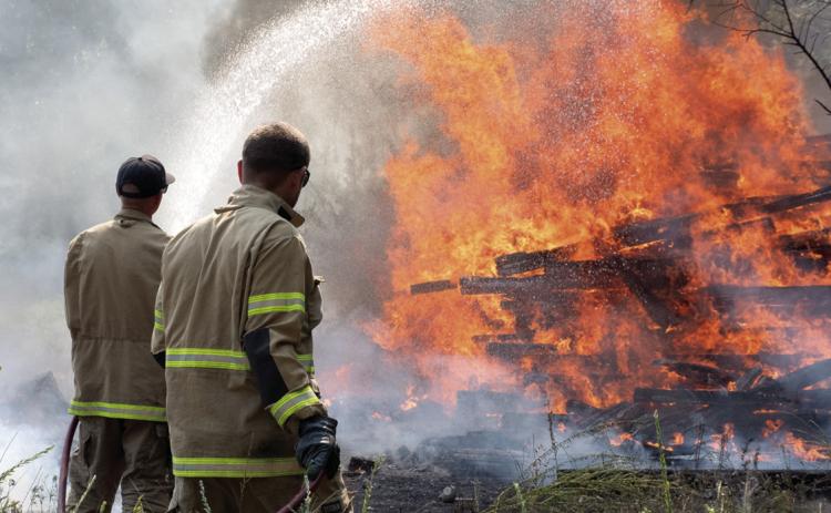 What started as a small fire Monday afternoon quickly spread to engulf multipole acres including a file of more than a hundred railroad ties. Columbus Fire Fighters Kale Kitterman and Cody Burton work to contain the large fire as part of a six-man, three apparatus crew that responded to the fire.