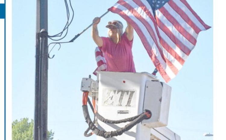 Though not a patriotic holiday, City of Columbus employee Kasie England worked Friday placing the U.S. flags on light poles down Maple Street and around the square for the Labor Day holiday.