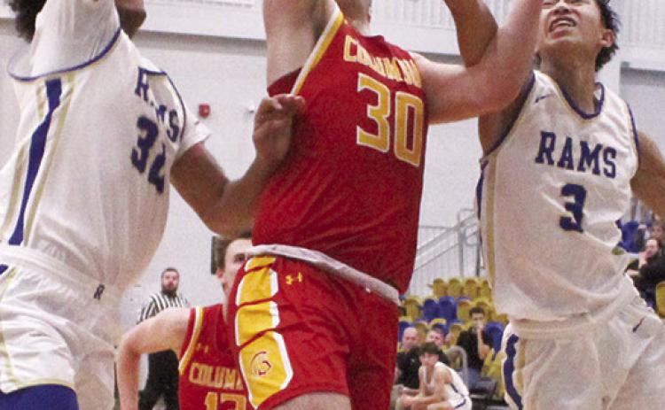 Titan Senior, Brett Hamilton, goes in for two points between Ram Senior, Jamey Richardson and junior, Zach Feldkamp in the final minutes of the, 59-48, Columbus win in Riverton, Friday.