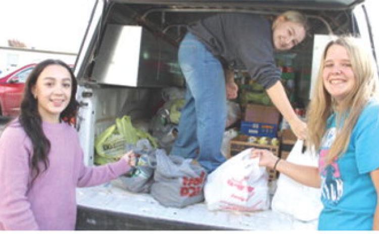 Hannah Noel, Amory Neely and Morgan Richards helped unload groceries to be placed in the Thanksgiving meal boxes. The boxes were distributed Tuesday before Thanksgiving.