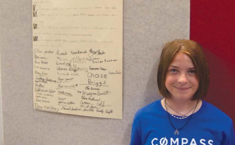 Standing beside the Classroom Constitution developed by the Compass Academy students during their recent session. Misty Daniels is pictured by the Civics work.