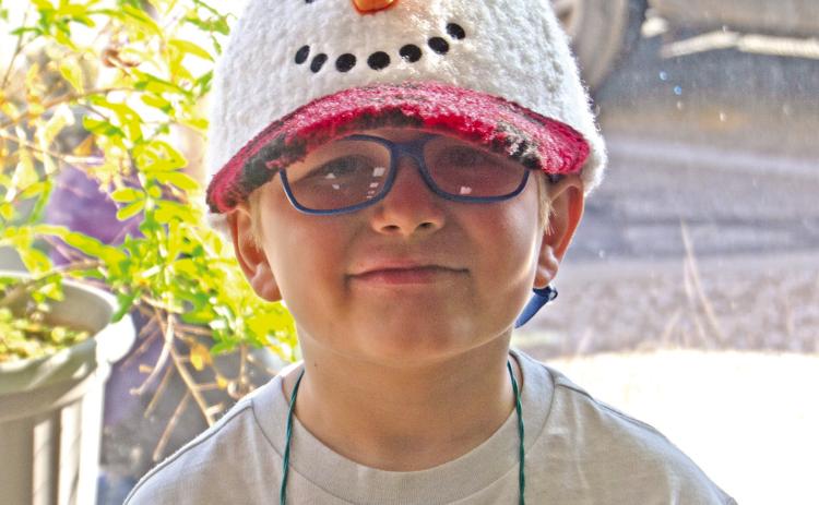 The weather might have been warm, but Manny Napier sported his snowman cap while the second grade classes sang carols around the square before Christmas break. News Report photo by Shawn Churchill.